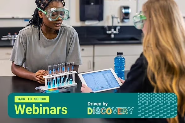 image of two people in a lab sitting at a bench looking at test tubes and spectra on an electronic tablet